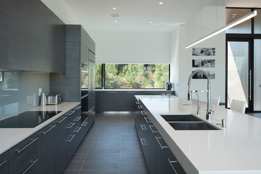 Photo of a mid-sized contemporary galley kitchen in Phoenix with flat-panel cabinets, grey splashback, glass sheet splashback and with island.