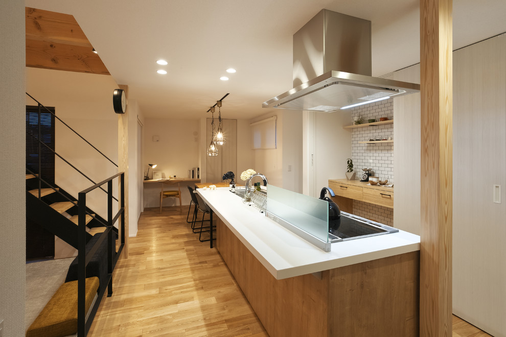 Mid-sized scandinavian galley open plan kitchen in Other with a single-bowl sink, beaded inset cabinets, light wood cabinets, solid surface benchtops, light hardwood floors, a peninsula and brown floor.