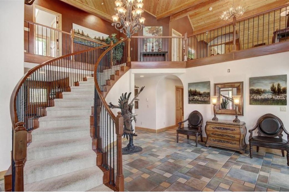 Photo of a large country foyer in Denver with brown walls, porcelain floors, multi-coloured floor, vaulted and wood walls.
