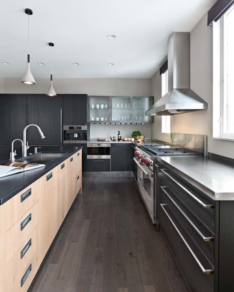 Large contemporary l-shaped kitchen in Detroit with an undermount sink, flat-panel cabinets, black cabinets, quartz benchtops, panelled appliances, with island and dark hardwood floors.