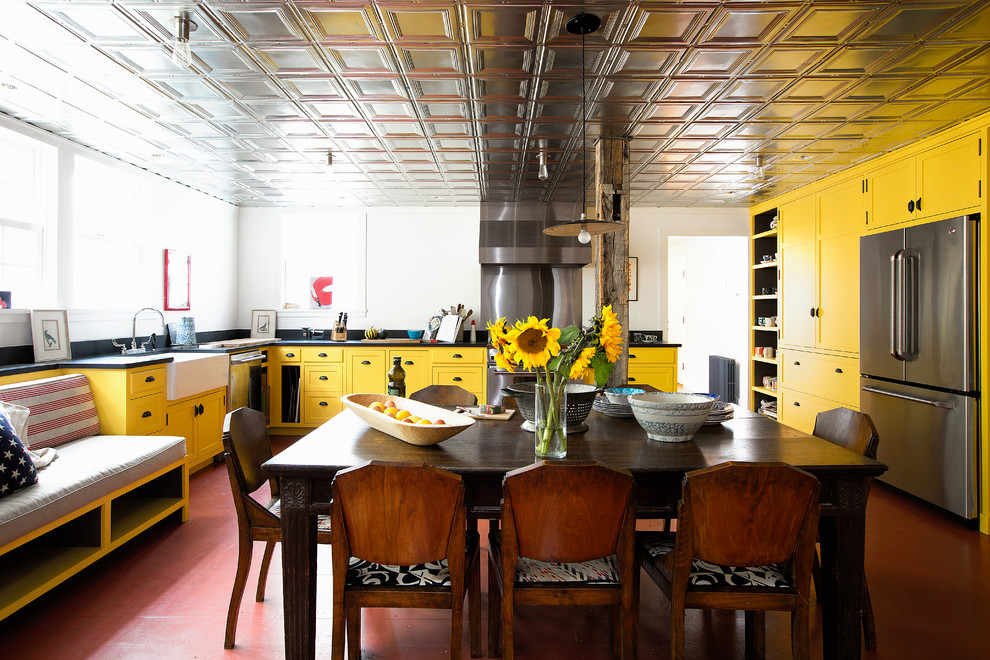 Inspiration for a country u-shaped eat-in kitchen in New York with a farmhouse sink, shaker cabinets, yellow cabinets, white splashback, stainless steel appliances, red floor and black benchtop.