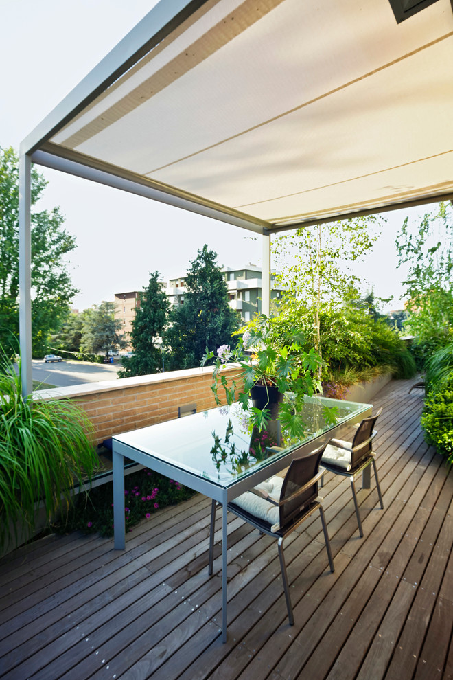 This is an example of a contemporary backyard deck in Bologna with a container garden and a pergola.