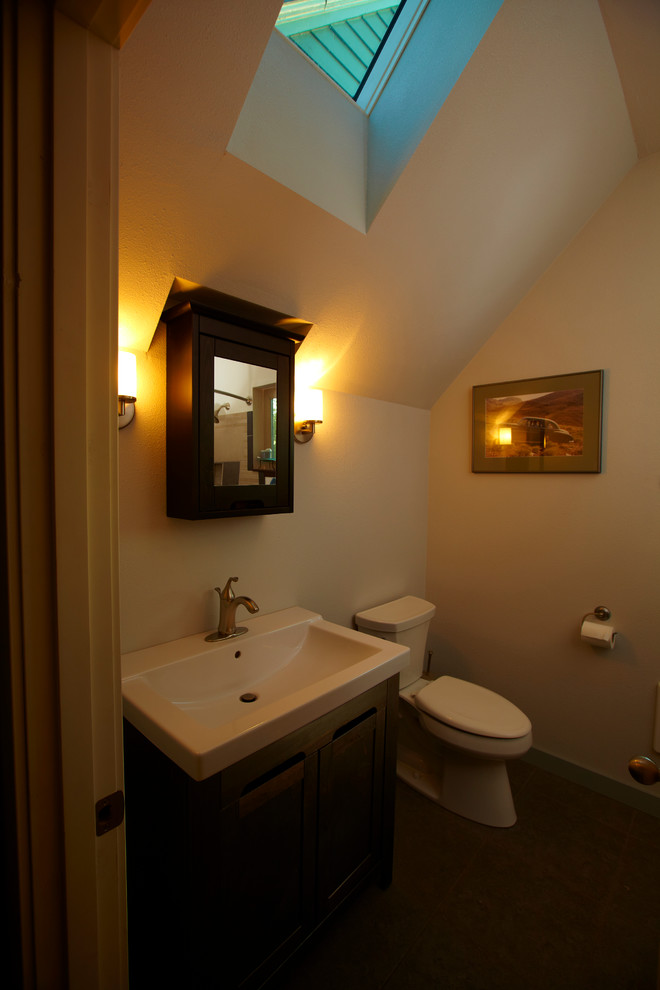 Small transitional home design photo with raised-panel cabinets, brown cabinets, a two-piece toilet and an integrated sink