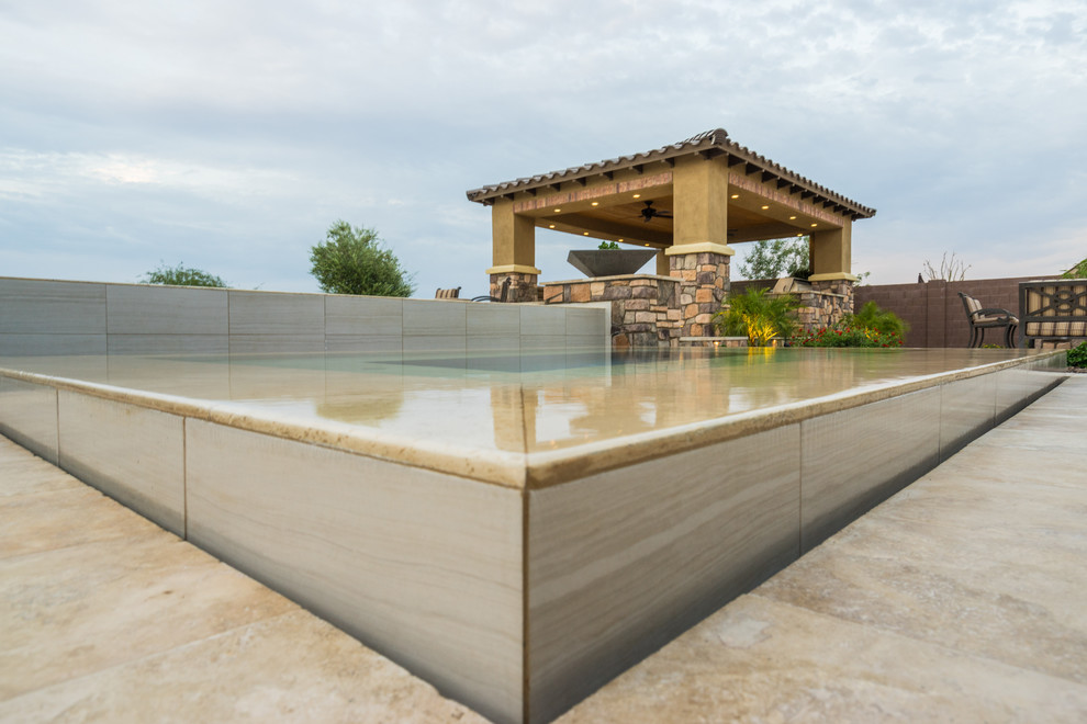 Design ideas for a large backyard rectangular infinity pool in Phoenix with a hot tub and natural stone pavers.