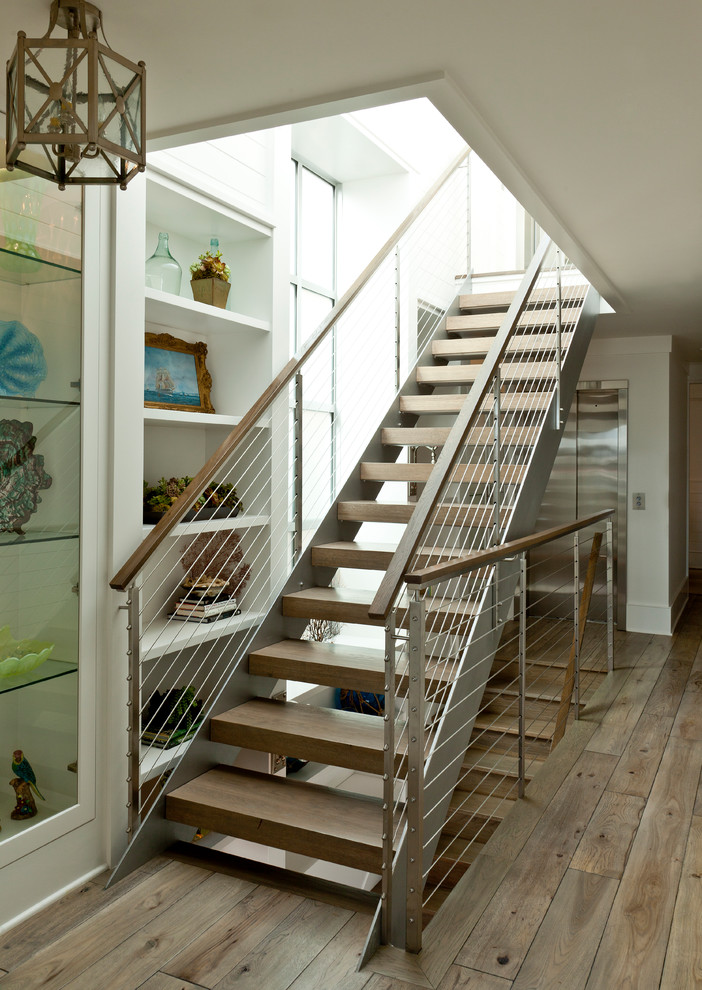 Mid-sized beach style wood straight staircase in Orange County with open risers and cable railing.