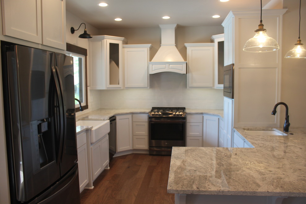 Large transitional u-shaped laminate floor and beige floor enclosed kitchen photo with an undermount sink, raised-panel cabinets, white cabinets, quartzite countertops, white backsplash, ceramic backsplash, stainless steel appliances, an island and white countertops