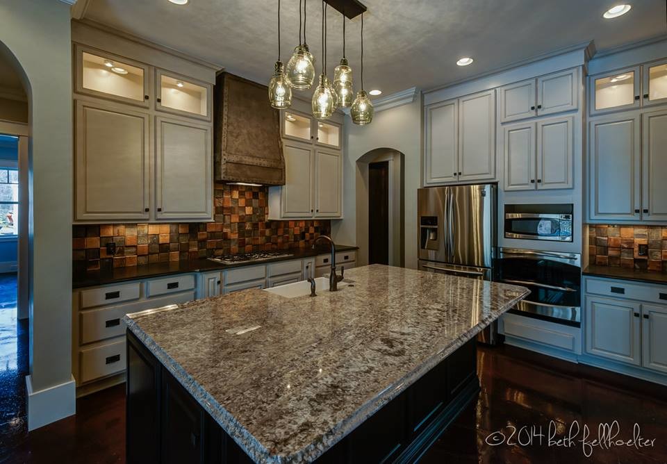 Exempel på ett klassiskt kök, med en rustik diskho, luckor med upphöjd panel, vita skåp, granitbänkskiva, flerfärgad stänkskydd, rostfria vitvaror, betonggolv och en köksö