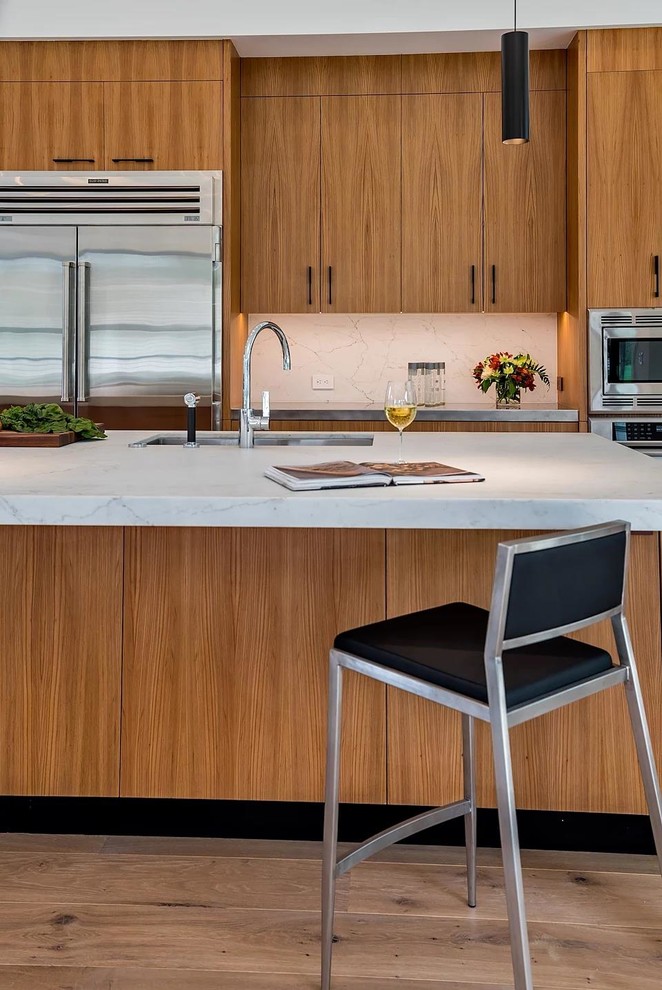 Photo of a large modern u-shaped eat-in kitchen in San Francisco with an undermount sink, flat-panel cabinets, medium wood cabinets, quartz benchtops, white splashback, stone slab splashback, stainless steel appliances, light hardwood floors, with island, brown floor and white benchtop.