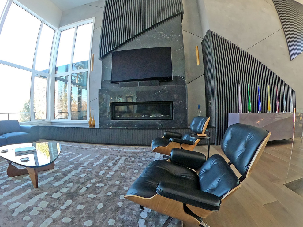 Geräumiges, Offenes Stilmix Wohnzimmer mit grauer Wandfarbe, braunem Holzboden, Gaskamin, Kaminumrandung aus Stein, braunem Boden und Holzwänden in Calgary