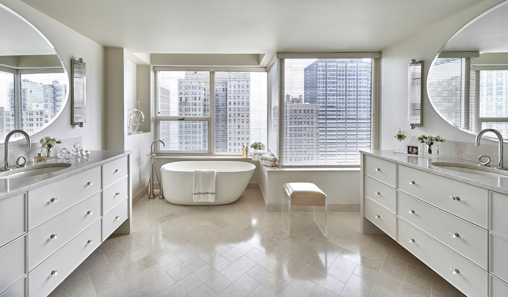 Inspiration for a large transitional master bathroom in Chicago with white cabinets, white walls, an undermount sink, beige floor, marble benchtops, a freestanding tub, an alcove shower, beige tile, travertine, travertine floors, a hinged shower door and flat-panel cabinets.