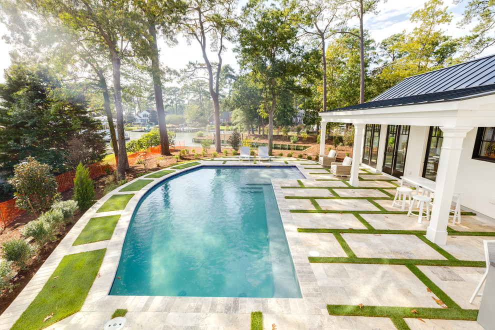 This is an example of a large modern backyard custom-shaped natural pool in Other with a pool house and natural stone pavers.