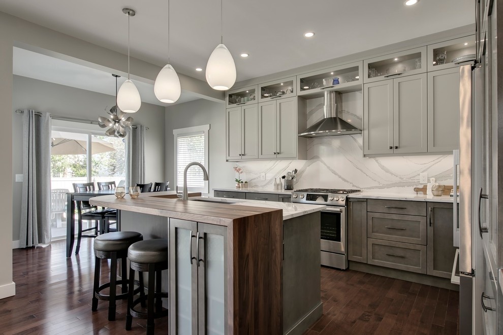 Eat-in kitchen - large transitional u-shaped dark wood floor and brown floor eat-in kitchen idea in Calgary with an undermount sink, recessed-panel cabinets, gray cabinets, quartzite countertops, white backsplash, stone slab backsplash, stainless steel appliances, an island and white countertops