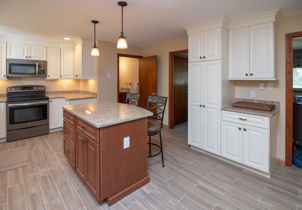 Mid-sized transitional l-shaped eat-in kitchen in Boston with a double-bowl sink, raised-panel cabinets, white cabinets, quartz benchtops, stainless steel appliances, porcelain floors, with island, brown floor and brown benchtop.
