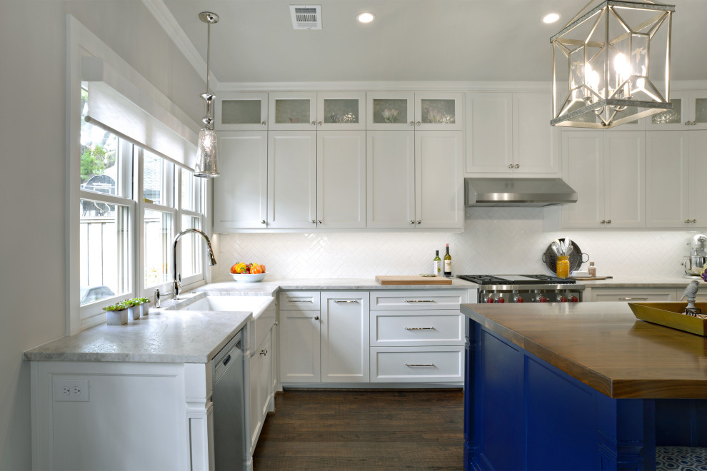 Design ideas for a transitional l-shaped eat-in kitchen in Dallas with a farmhouse sink, shaker cabinets, white cabinets, quartzite benchtops, white splashback, subway tile splashback, stainless steel appliances, medium hardwood floors, with island, brown floor and grey benchtop.