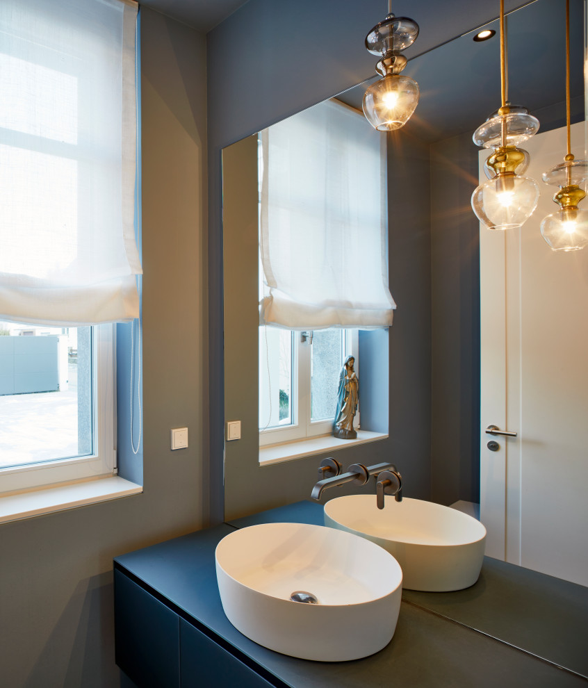 Photo of a small contemporary powder room in Frankfurt with flat-panel cabinets, blue cabinets, blue walls, cement tiles, a vessel sink, blue benchtops and a floating vanity.