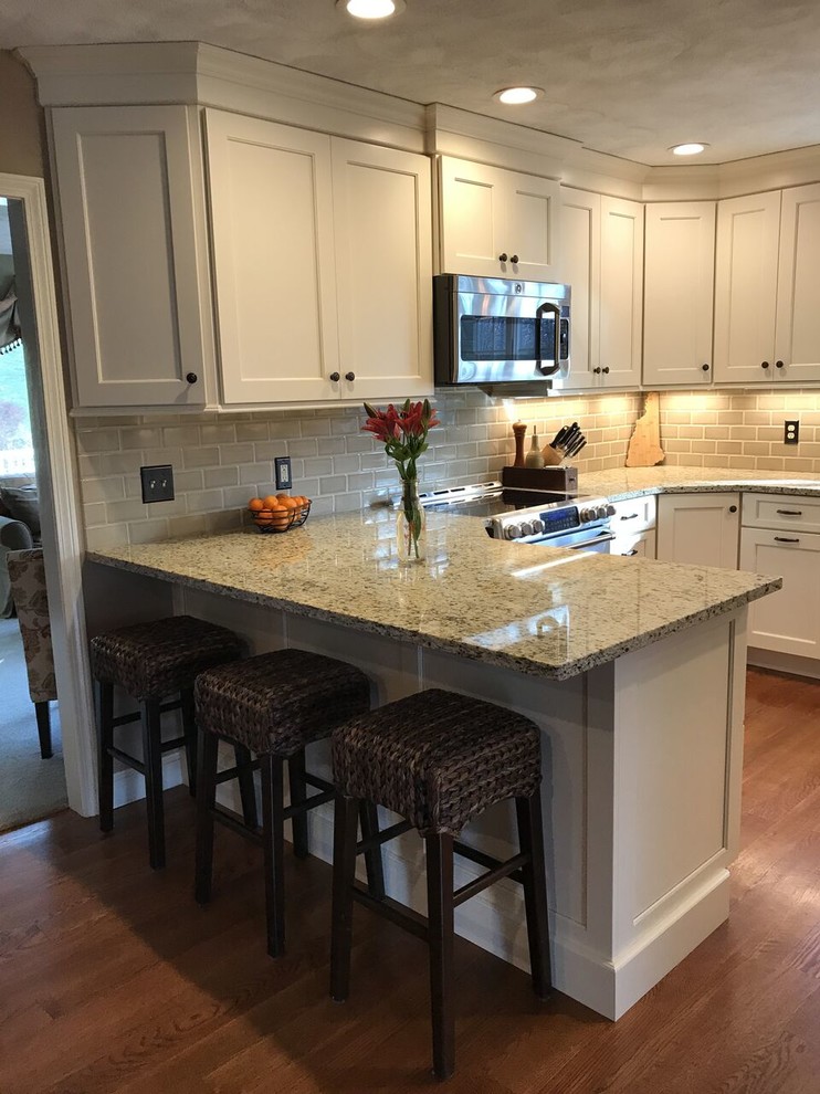 Eat-in kitchen - transitional u-shaped medium tone wood floor eat-in kitchen idea in Boston with an undermount sink, shaker cabinets, white cabinets, granite countertops, beige backsplash, subway tile backsplash, stainless steel appliances and a peninsula