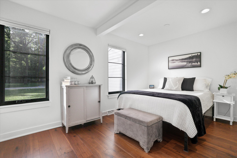 Idee per una camera matrimoniale minimalista di medie dimensioni con pareti bianche, pavimento in laminato, pavimento marrone e travi a vista