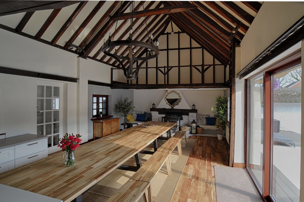 Inspiration for a large country dining room in Other with white walls, dark hardwood floors, a standard fireplace, a brick fireplace surround and brown floor.