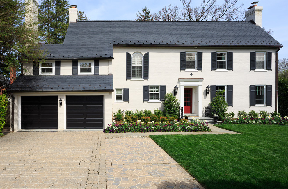 Photo of a large traditional two-storey stucco beige house exterior in DC Metro with a gable roof and a shingle roof.