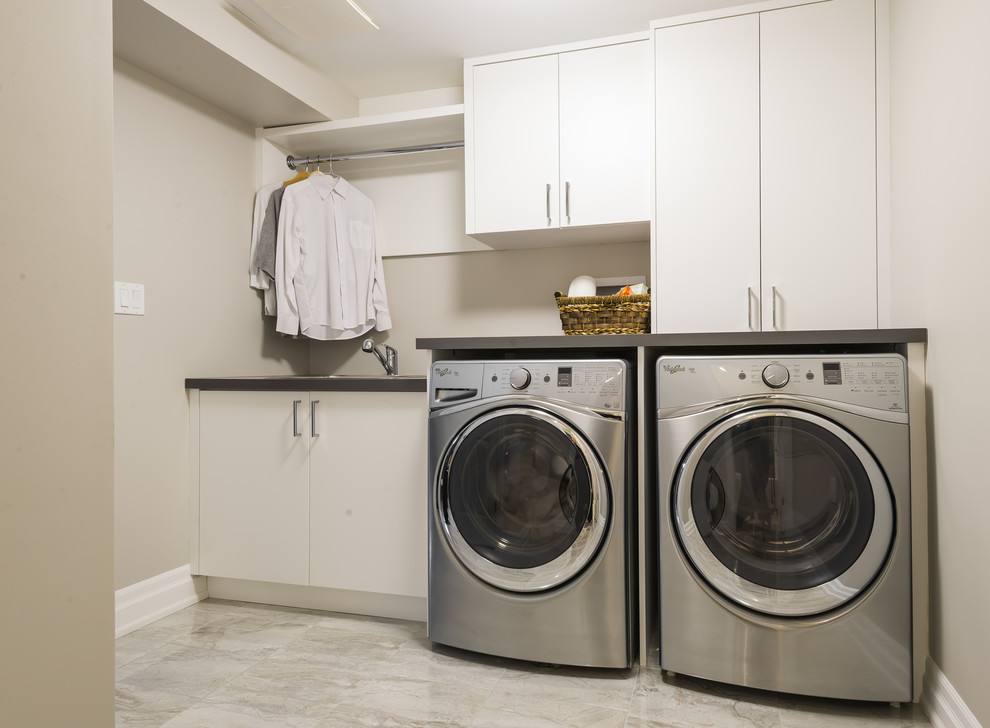 Inspiration for a mid-sized transitional single-wall ceramic tile dedicated laundry room remodel in Toronto with a drop-in sink, flat-panel cabinets, white cabinets, laminate countertops, beige walls and a side-by-side washer/dryer