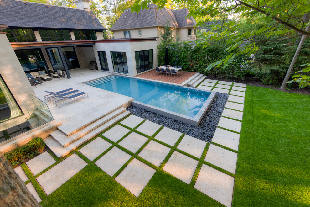 Example of a large trendy backyard stone and rectangular infinity pool fountain design