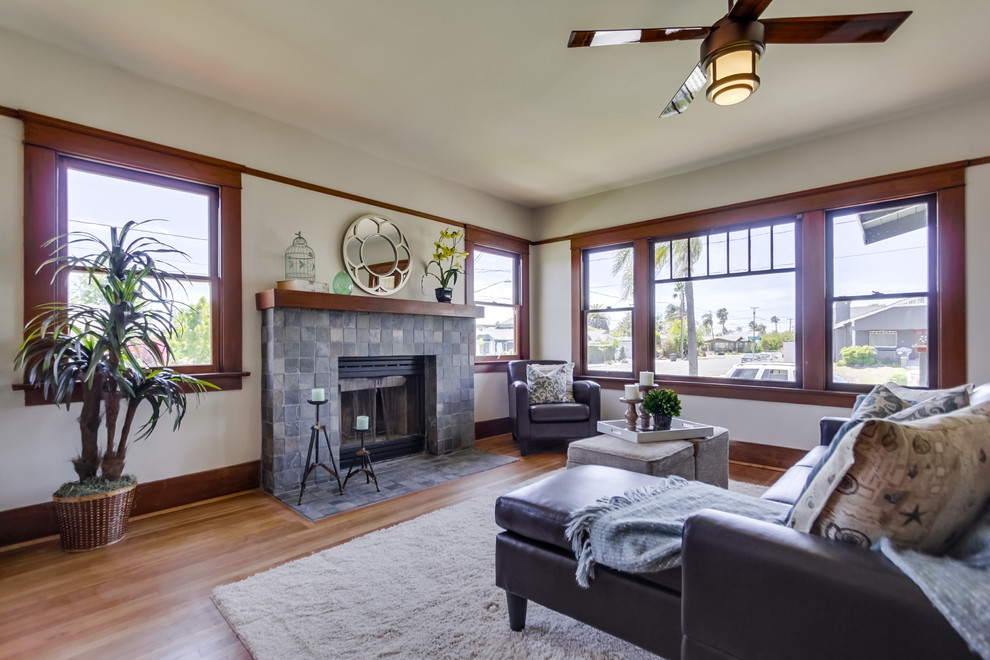 This is an example of a mid-sized arts and crafts formal enclosed living room in San Diego with grey walls, light hardwood floors, a standard fireplace and a stone fireplace surround.