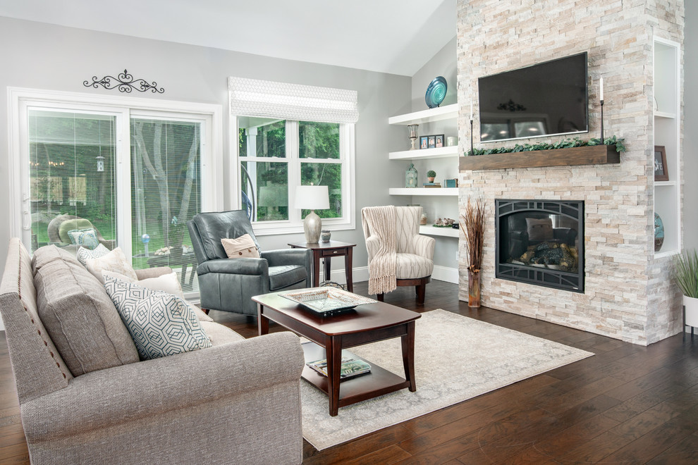 This is an example of a transitional open concept living room in Other with grey walls, dark hardwood floors, a standard fireplace, a stone fireplace surround, a wall-mounted tv and brown floor.