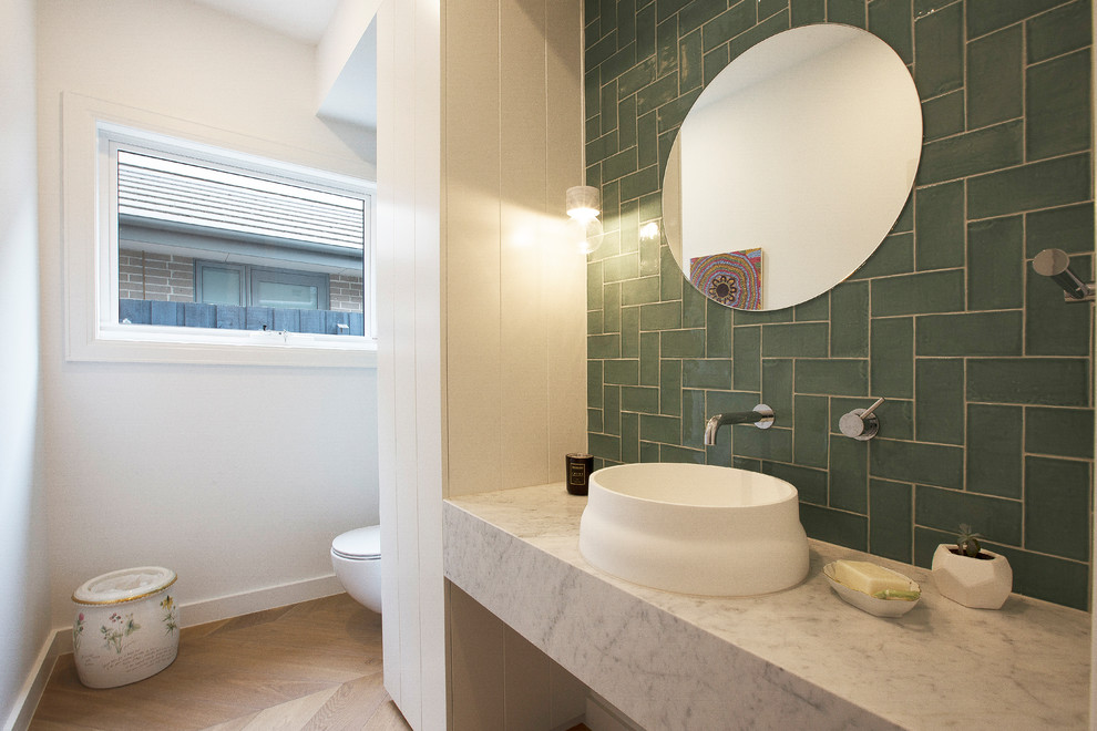 Photo of a modern powder room in Melbourne with green tile, white walls, medium hardwood floors, a vessel sink, beige floor and grey benchtops.