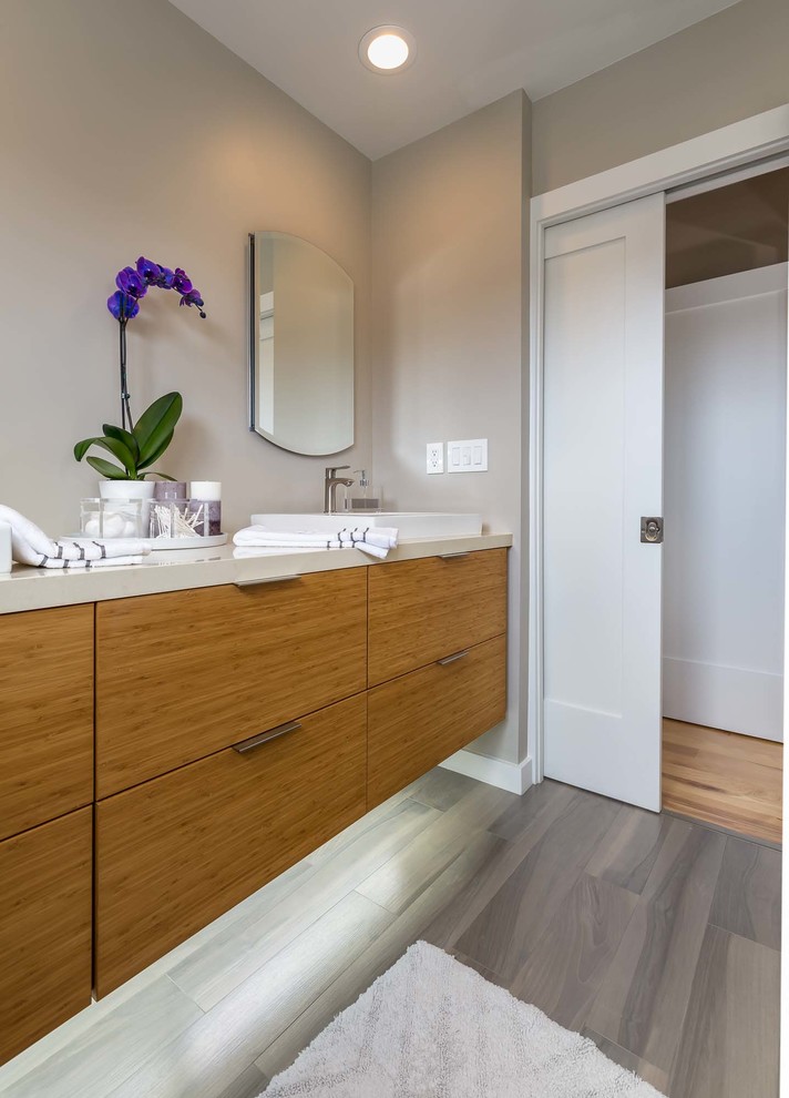 This is an example of a mid-sized contemporary master bathroom in Los Angeles with flat-panel cabinets, light wood cabinets, a curbless shower, a two-piece toilet, beige tile, travertine, beige walls, porcelain floors, a vessel sink, engineered quartz benchtops, brown floor and a sliding shower screen.