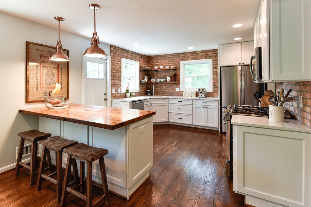 Inspiration for a mid-sized country u-shaped separate kitchen in DC Metro with an undermount sink, white cabinets, stainless steel appliances, shaker cabinets, wood benchtops, red splashback, brick splashback, dark hardwood floors, a peninsula and brown floor.