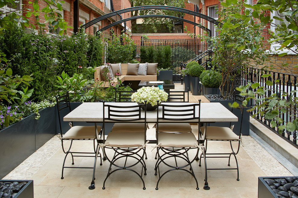 This is an example of a traditional courtyard patio in London with tile.