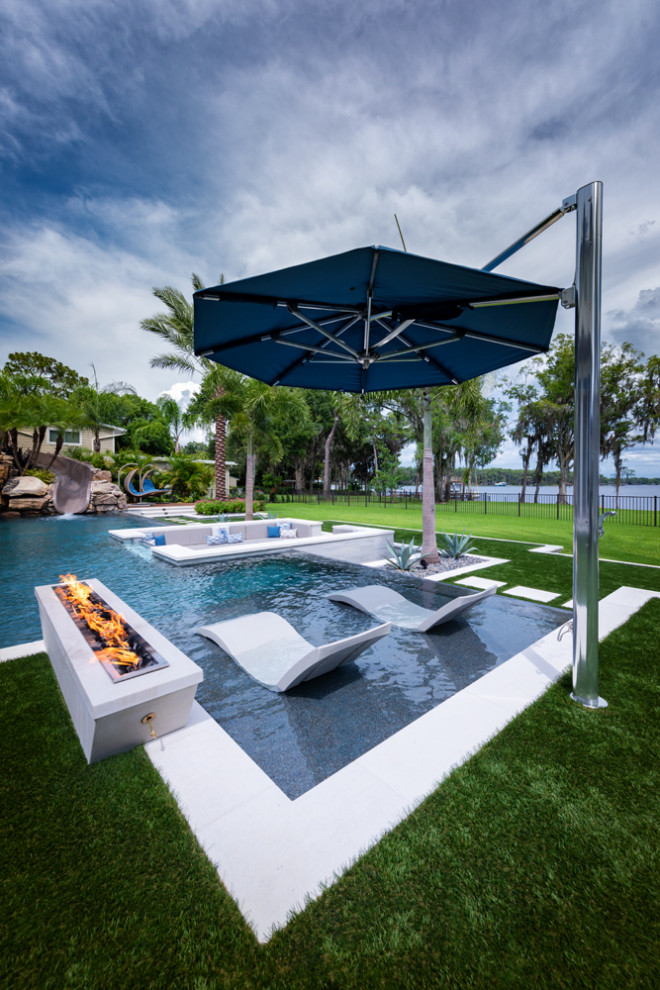 Ispirazione per una grande piscina a sfioro infinito minimal personalizzata dietro casa con paesaggistica bordo piscina e piastrelle