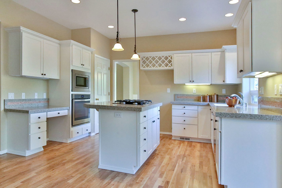 Inspiration for a mid-sized transitional u-shaped light wood floor and beige floor open concept kitchen remodel with an undermount sink, shaker cabinets, white cabinets, granite countertops, stainless steel appliances and an island
