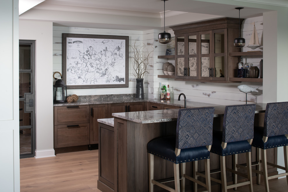 This is an example of a large arts and crafts u-shaped seated home bar in Minneapolis with no sink, shaker cabinets, dark wood cabinets, granite benchtops, white splashback, timber splashback, medium hardwood floors, brown floor and grey benchtop.