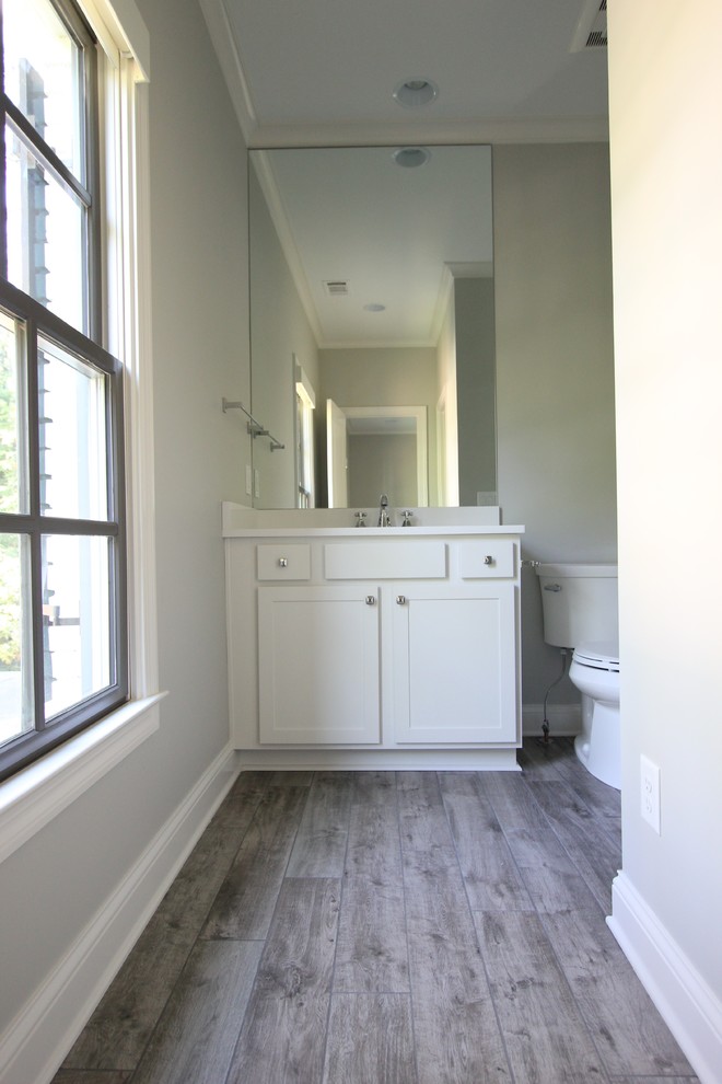 Photo of an expansive transitional master bathroom in Atlanta with shaker cabinets, white cabinets, medium hardwood floors, engineered quartz benchtops, a one-piece toilet, grey walls and a wall-mount sink.