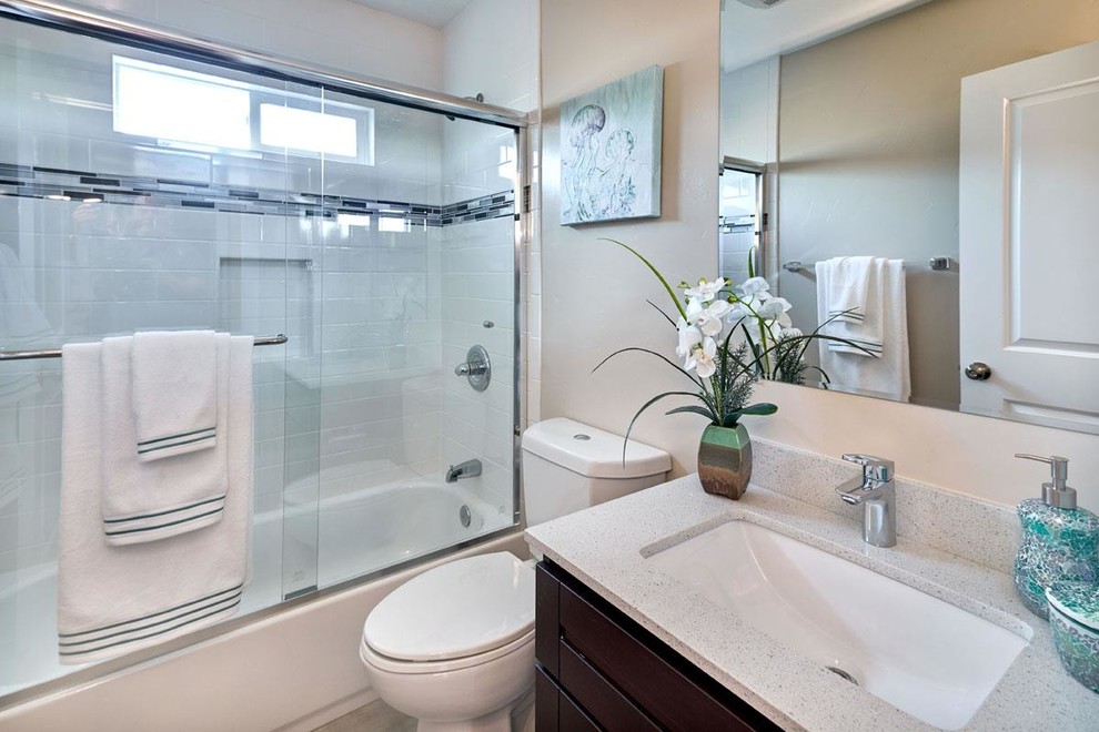 Small contemporary bathroom in San Francisco with raised-panel cabinets, dark wood cabinets, a drop-in tub, a shower/bathtub combo, a two-piece toilet, white tile, cement tile, beige walls, ceramic floors, an undermount sink and engineered quartz benchtops.