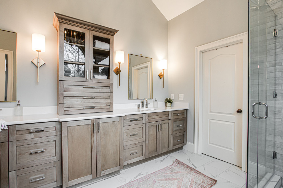 This is an example of a mid-sized transitional master bathroom in Atlanta with shaker cabinets, light wood cabinets, a freestanding tub, an alcove shower, a one-piece toilet, white tile, porcelain tile, blue walls, porcelain floors, a drop-in sink, engineered quartz benchtops, white floor, a hinged shower door, white benchtops, a niche, a double vanity, a built-in vanity and vaulted.