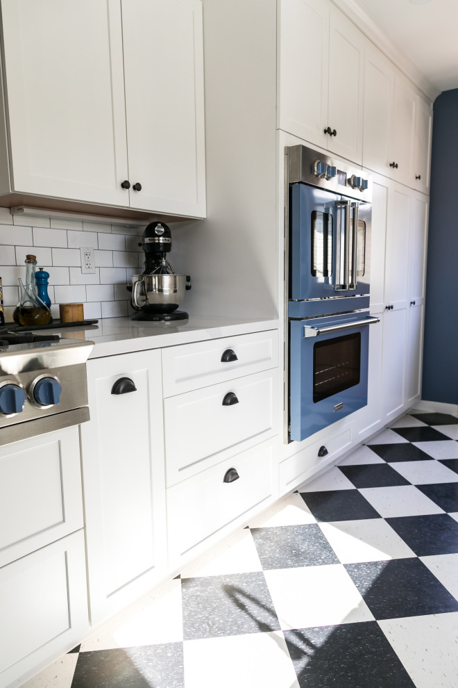 Inspiration for a mid-sized eclectic galley vinyl floor and black floor eat-in kitchen remodel in San Francisco with a farmhouse sink, shaker cabinets, white cabinets, quartz countertops, white backsplash, ceramic backsplash, colored appliances, no island and white countertops