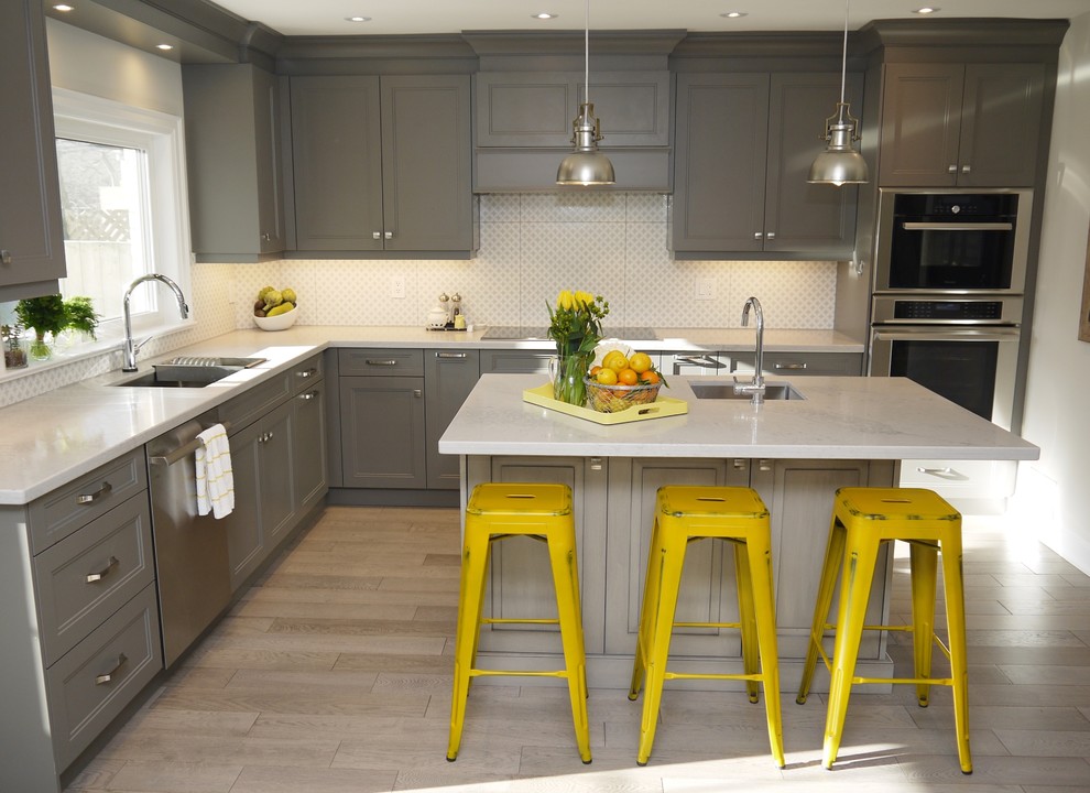 Enclosed kitchen - mid-sized transitional l-shaped light wood floor enclosed kitchen idea in Toronto with an undermount sink, recessed-panel cabinets, gray cabinets, quartz countertops, white backsplash, porcelain backsplash, stainless steel appliances and an island