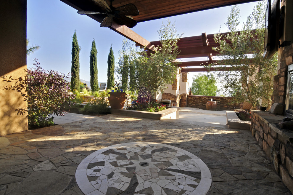 Large tuscan backyard stone patio fountain photo in Orange County with a roof extension