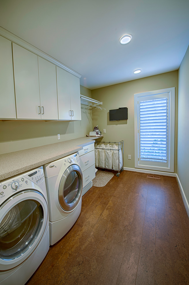 Inspiration for a traditional single-wall laundry room in Philadelphia with flat-panel cabinets, white cabinets, beige walls, cork floors and a side-by-side washer and dryer.