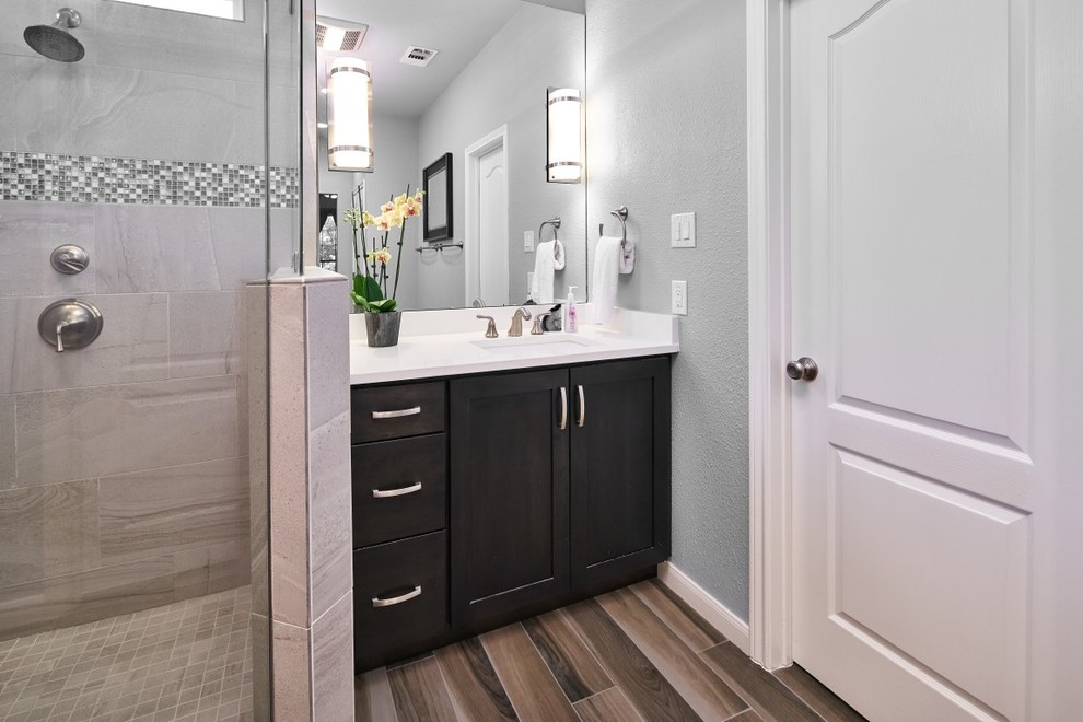 Inspiration for a transitional master beige tile and porcelain tile porcelain tile corner shower remodel in Austin with shaker cabinets, dark wood cabinets, gray walls, an undermount sink, quartz countertops and a hinged shower door