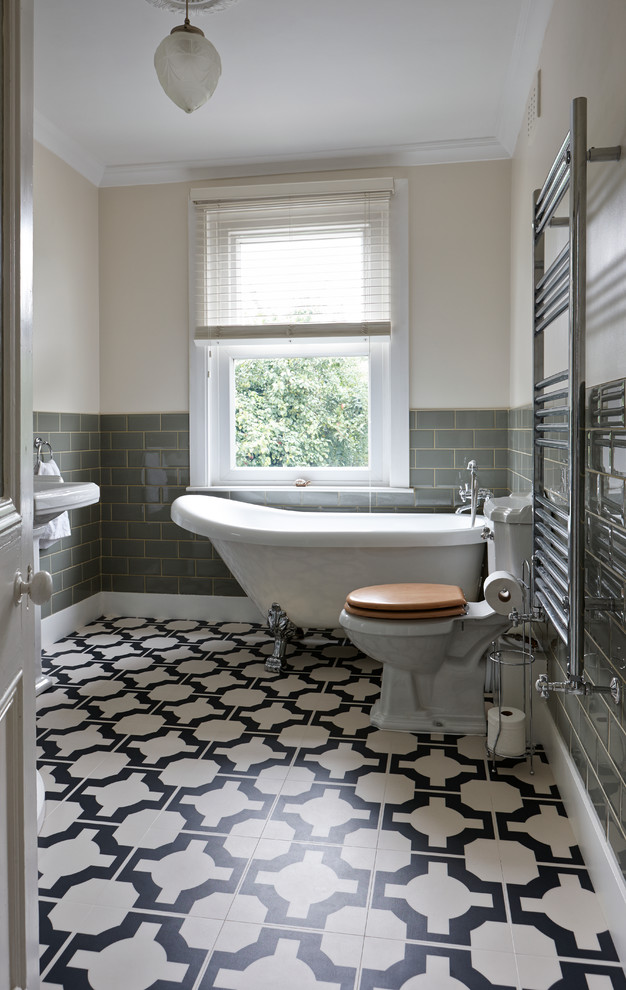 Photo of a mid-sized traditional kids bathroom in Manchester with a freestanding tub, a one-piece toilet, gray tile, ceramic tile, white walls, vinyl floors and a pedestal sink.