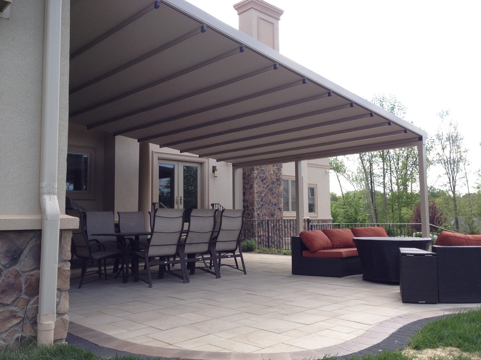 This is an example of a mid-sized transitional backyard patio in New York with decking and an awning.
