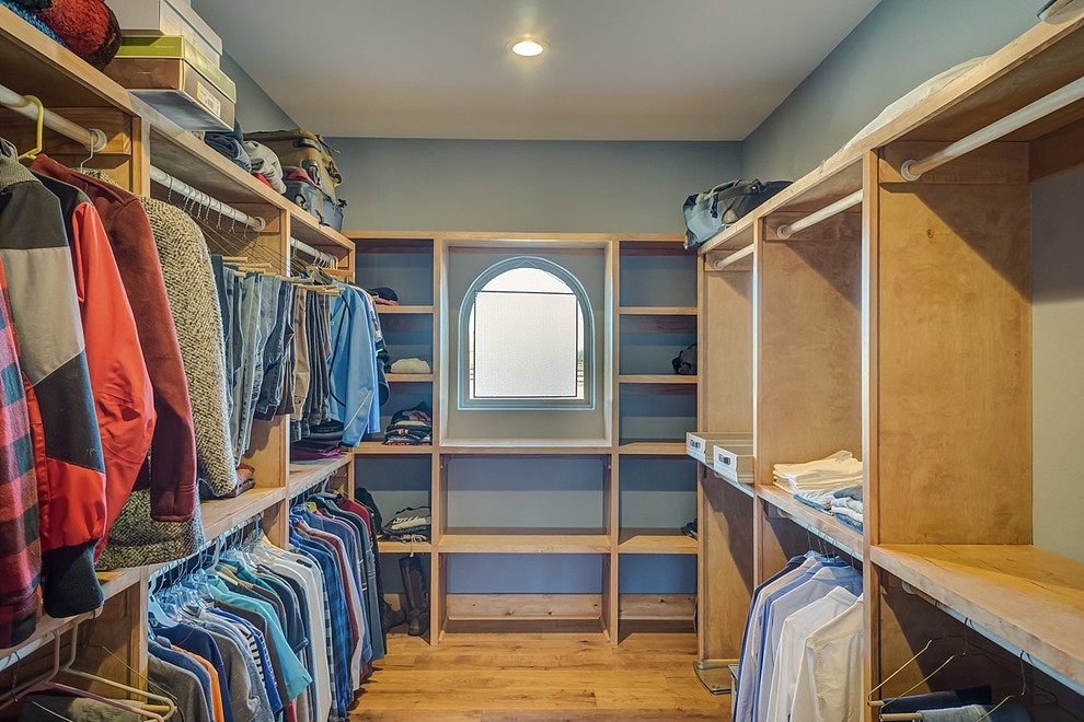 This is an example of a large country gender-neutral walk-in wardrobe in Dallas with open cabinets, light wood cabinets and medium hardwood floors.