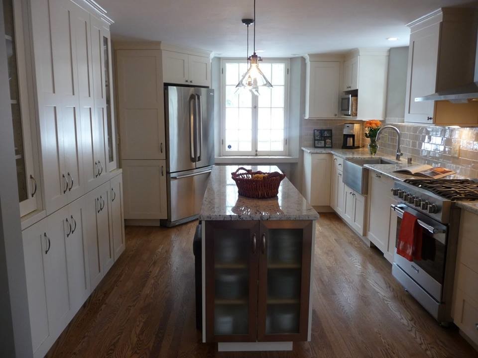 Eat-in kitchen - large transitional u-shaped light wood floor eat-in kitchen idea in Milwaukee with a farmhouse sink, recessed-panel cabinets, white cabinets, granite countertops, gray backsplash, subway tile backsplash, stainless steel appliances and an island