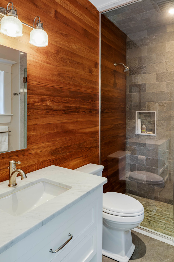 Traditional kids bathroom in Boston with shaker cabinets, white cabinets, an open shower, a one-piece toilet, gray tile, stone tile, brown walls, ceramic floors, an undermount sink, marble benchtops, grey floor, a hinged shower door and white benchtops.