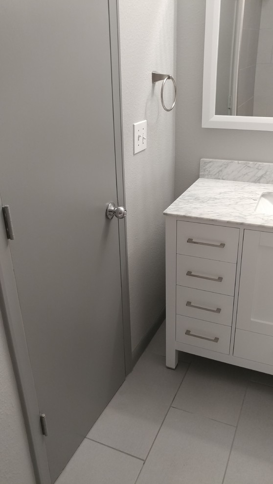 This is an example of a small transitional kids bathroom in Dallas with shaker cabinets, white cabinets, an alcove tub, a shower/bathtub combo, a two-piece toilet, gray tile, porcelain tile, grey walls, porcelain floors, an undermount sink, marble benchtops, grey floor and a sliding shower screen.
