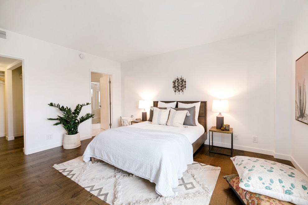 Photo of a beach style master bedroom in Los Angeles with white walls, medium hardwood floors and brown floor.