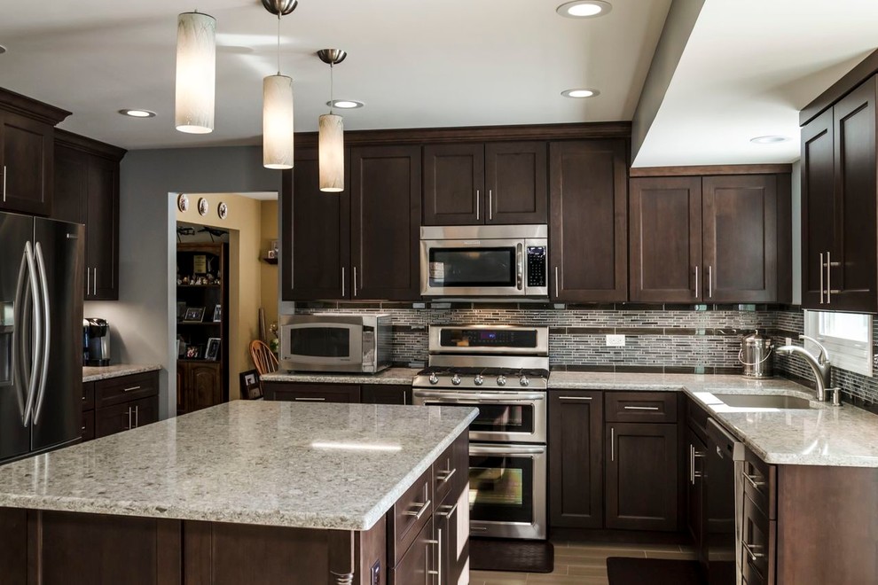 Mid-sized transitional l-shaped porcelain tile open concept kitchen photo in Chicago with an undermount sink, raised-panel cabinets, dark wood cabinets, quartz countertops, stainless steel appliances, blue walls, gray backsplash and matchstick tile backsplash